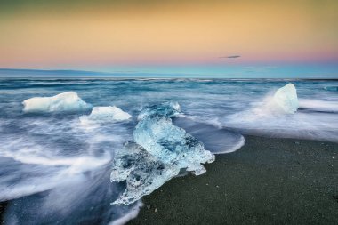 Gün batımında Jokulsarlon lagünündeki ünlü Diamond Sahili 'nde buzdağının dokunulabilir parçaları parlıyor. Konum: Jokulsarlon Lagünü, Diamond Sahili, Vatnajokull Ulusal Parkı, İzlanda, Avrupa