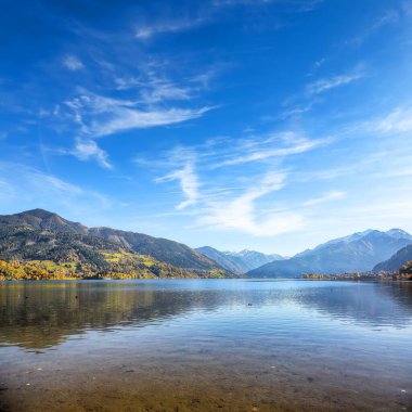 Sell Am See 'deki göl ve ağaçların olağanüstü sonbahar manzarası. Gölün üzerinde güneşli harika bir gün.