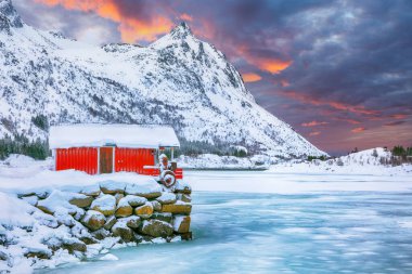 Rolvsfjord sahilinde geleneksel Norveç kırmızı ahşap evleri olan inanılmaz kış manzarası. Konum: Vestvagoy, Rolvsfjord, Lofotens, Norveç, Avrupa.