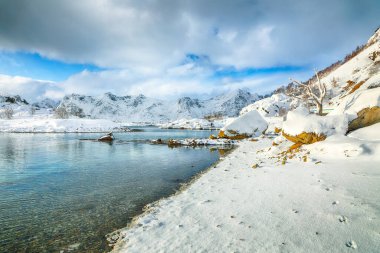 Küçük bir balıkçı köyünde çok kar ve Valberg yakınlarındaki karlı dağ zirveleriyle muhteşem bir kış manzarası. Konum: Valberg, Vestvagoy, Lofotens, Norveç
