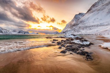 Gün batımında Haukland plajı ve Leknes yakınlarında karlı dağ zirveleri ile inanılmaz bir kış manzarası. Konum: Leknes, Vestvagoy, Lofotens, Norveç