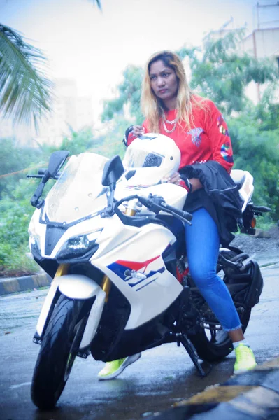 Düşünceli kadın motosiklette otururken gözlerini kaçırıyor.