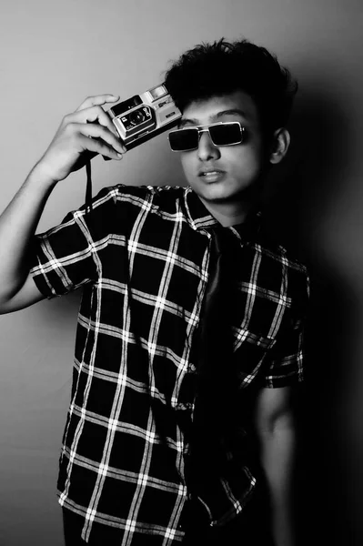 young boy wearing a sun glass and heaving a camera b&w image, portrait