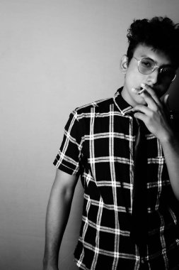 smoking young boy wearing sun glass and shirt with camera, black and white image