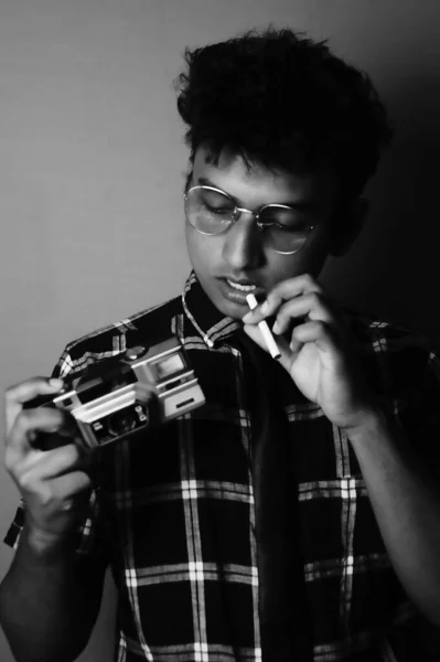 young boy wearing sun glass and shirt with camera,looking down black and white image