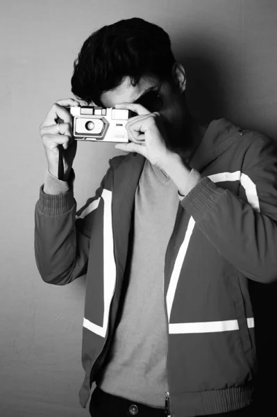young boy wearing jacket and black glass with camera, looking in camera black and white image