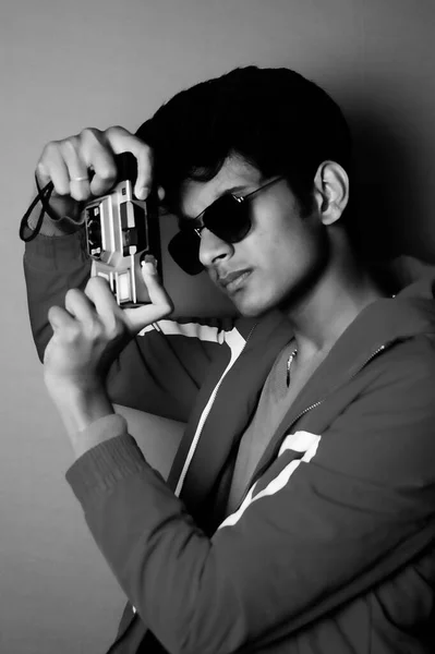 young boy wearing jacket and black glass with camera, taking photo black and white image