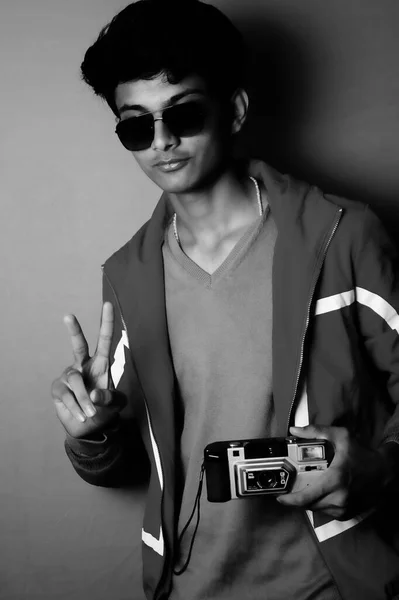 young boy wearing jacket and black glass with camera looking smart , black and white image