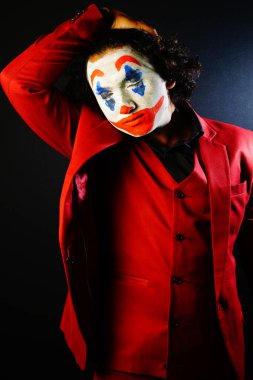 man with joker face , closed eyes in red formal image