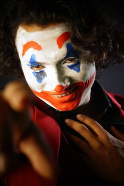 man in joker face makeup , with scary smile in formal outfit , picture