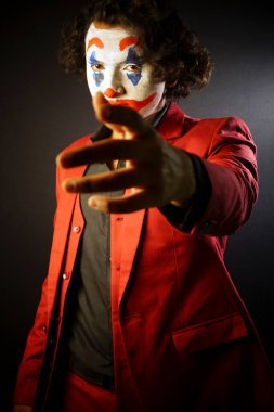 man in joker face makeup , looking front with in formal outfit