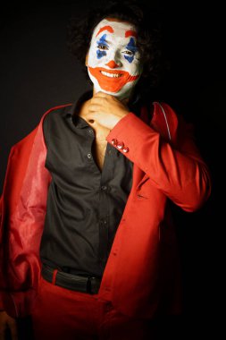 man in joker face makeup , in scary and crazy smile formal outfit, image