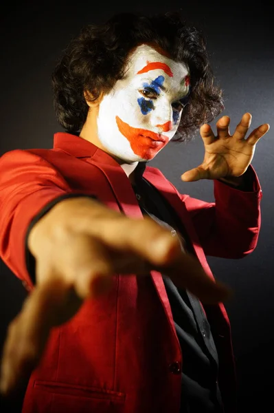 man in joker face makeup ,with evil pose in formal outfit