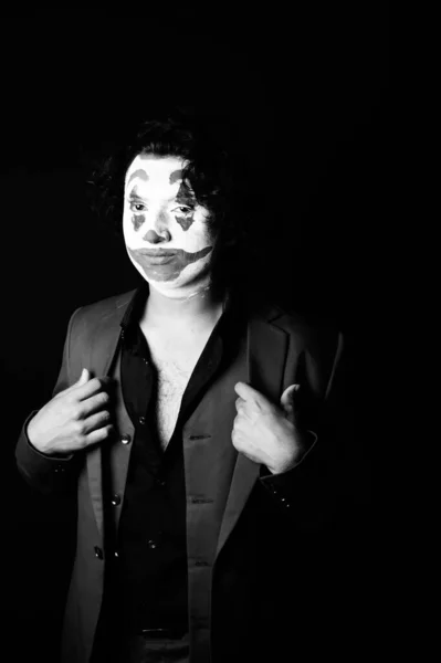 man in joker face makeup, in formal outfit ,black and whit image