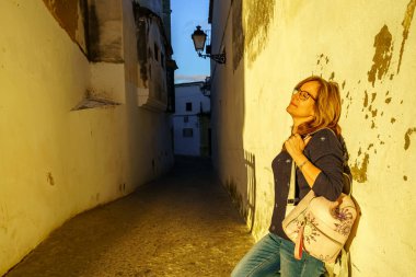 Beyaz kadın, Endülüs 'ün eski bir kasabasında beyaz bir duvarın yanında güneşli bir öğleden sonranın tadını çıkarıyor.