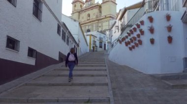 Cadiz 'deki Olvera köyünün tepesindeki katedrale giden basamaklarla sarp sokaklarda gezinen turist kadın.