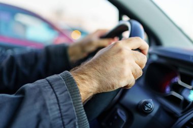 Mans hands taking the wheel of the car and driving at sunset.