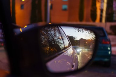 Rearview mirror of a car at night that reflects the lights of other vehicles circulating on the street
