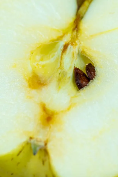 Interior of a yellow apple cut in half with its seeds peeking through the center of the apple, macrophotography