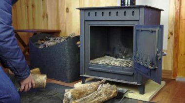 Man organizing the wood for a rustic stove to light the fire and heat the house