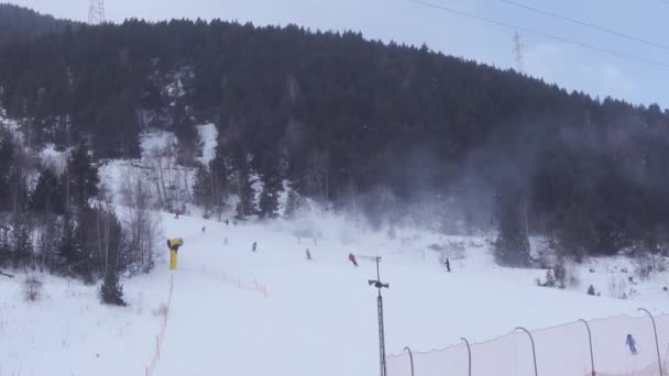 Skiërs Die Skipistes Afdalen Tussen Bergen Met Sneeuwkanonnen Die Sneeuw — Stockvideo