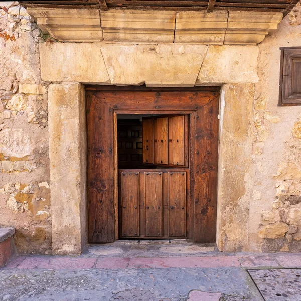 Old wooden door that opens in two parts in the stone houses of the medieval village of Pedraza, Segovia