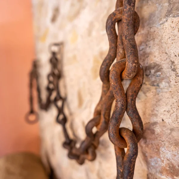 Long rusty chain placed on the stone wall for field work in the village of Pedraza