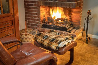Comfortable armchair in front of the fireplace fire to warm up in winter in a comfortable way