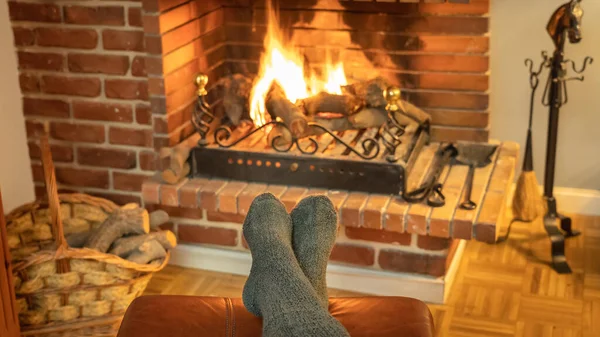 Feet with socks in front of the wood fireplace fire to warm them in winter