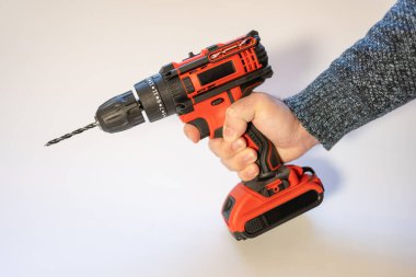 Mens hand holding an electric drill with batteries without cables on a white background