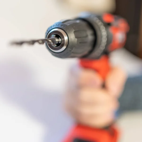 Mens hand holding an electric drill with batteries without cables on a white background