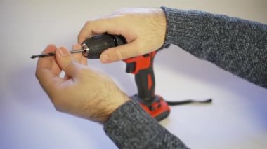 Mans hands putting a drill bit in the drill and making it work