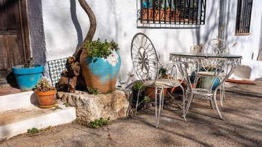 Facade of white houses with tables and chairs for sunbathing and pots with plants and flowers, Olmeda de las Fuentes, Madrid