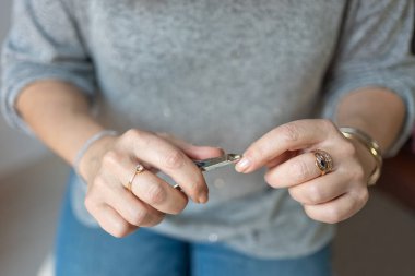 Yaşlı kadınların elleri küçük metal penseyle manikür yaparken.