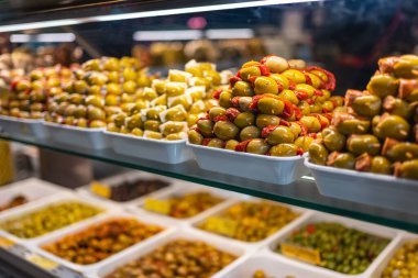 Renkli bir sergide yiyecek, zeytin ve turşu yığını olan Mercado San Miguel, Madrid pazarı.