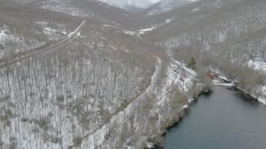Dağlar, Somosierra, Segovia, İspanya arasında gölü olan karlı bir ormanın hava aracı görüntüsü.