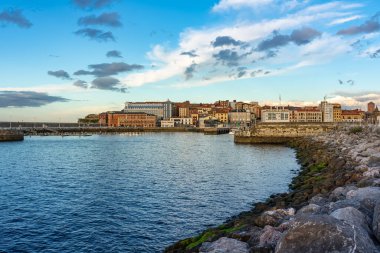İspanya 'nın Asturias eyaletinin Gijon kasabasında gün batımında konut binalarının yanındaki büyük kumlu plaj.