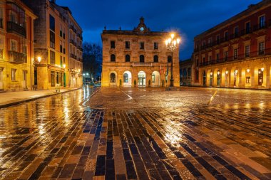 Yağmurlu bir günde, Asturias, İspanya, Asturias kaldırımlarındaki binaların yansımalarıyla dolu bir gecede Gijons ana meydanı.