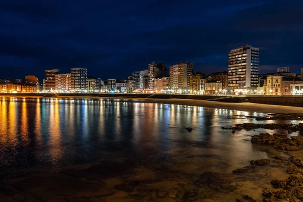 Promenade at night with reflections of lights and buildings in the sea water, Gijon, Asturias