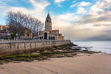 İspanya 'nın Gijon kıyı şehrinin plajında bulunan San Pedro kilisesinin yanında muhteşem bir gün doğumu.
