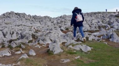 Kuzey İspanya, Asturias sahillerinde tuhaf kaya oluşumları arasında gezinen bir kadın.