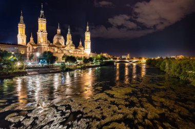 Geceleri Ebro nehrinin yanındaki Katedral Bazilikası del Pilar, nehre yansıdı ve aydınlandı, Zaragoza