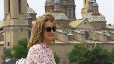 Zaragoza katedralinin yanında olgun bir kadın ve İspanyol şehrini tanımlayan güçlü rüzgara dayanır.
