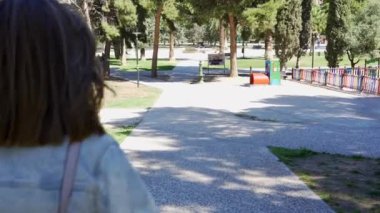 Rüzgarlı bir günde parkın içinde yürüyen beyaz bir kadın.