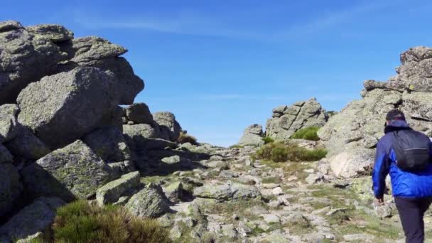 Człowiek Plecami Wspina Się Skalistą Górę Ścieżką Pomiędzy Dużymi Kamieniami — Wideo stockowe