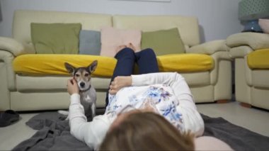 Kitap okuduktan sonra köpeğiyle oynarken yerde yatan beyaz kadın.