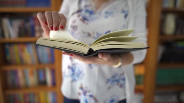Mujer Leyendo Libro Pasando Las Páginas Delante Una Librería Llena — Vídeos de Stock