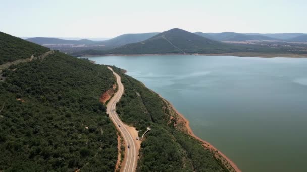スペイン中心部の穏やかな水の湖の隣に山を巻く道路 — ストック動画