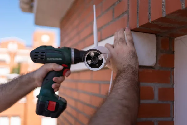 Man with a drill installing security cameras for surveillance in a house