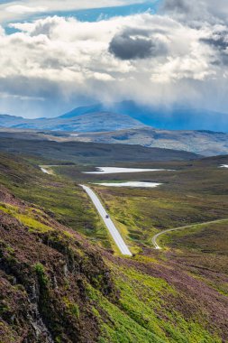 İskoçya, İngiltere 'de tek bir aracın dolaştığı yeşil dağların manzarası.